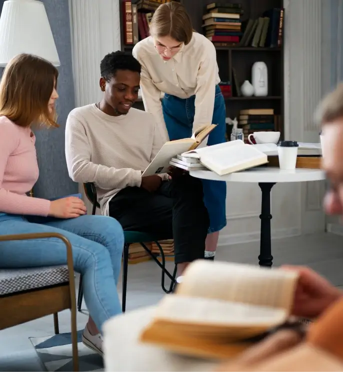 Three people reading a book around a coffee table